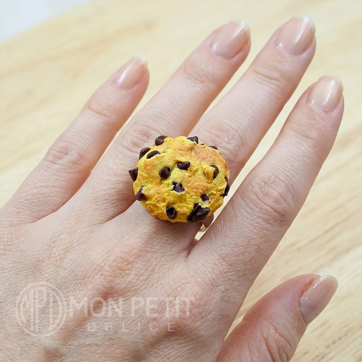 Cute chocolate chip cookie ring worn on a finger to show scale. Adjustable stainless steel band