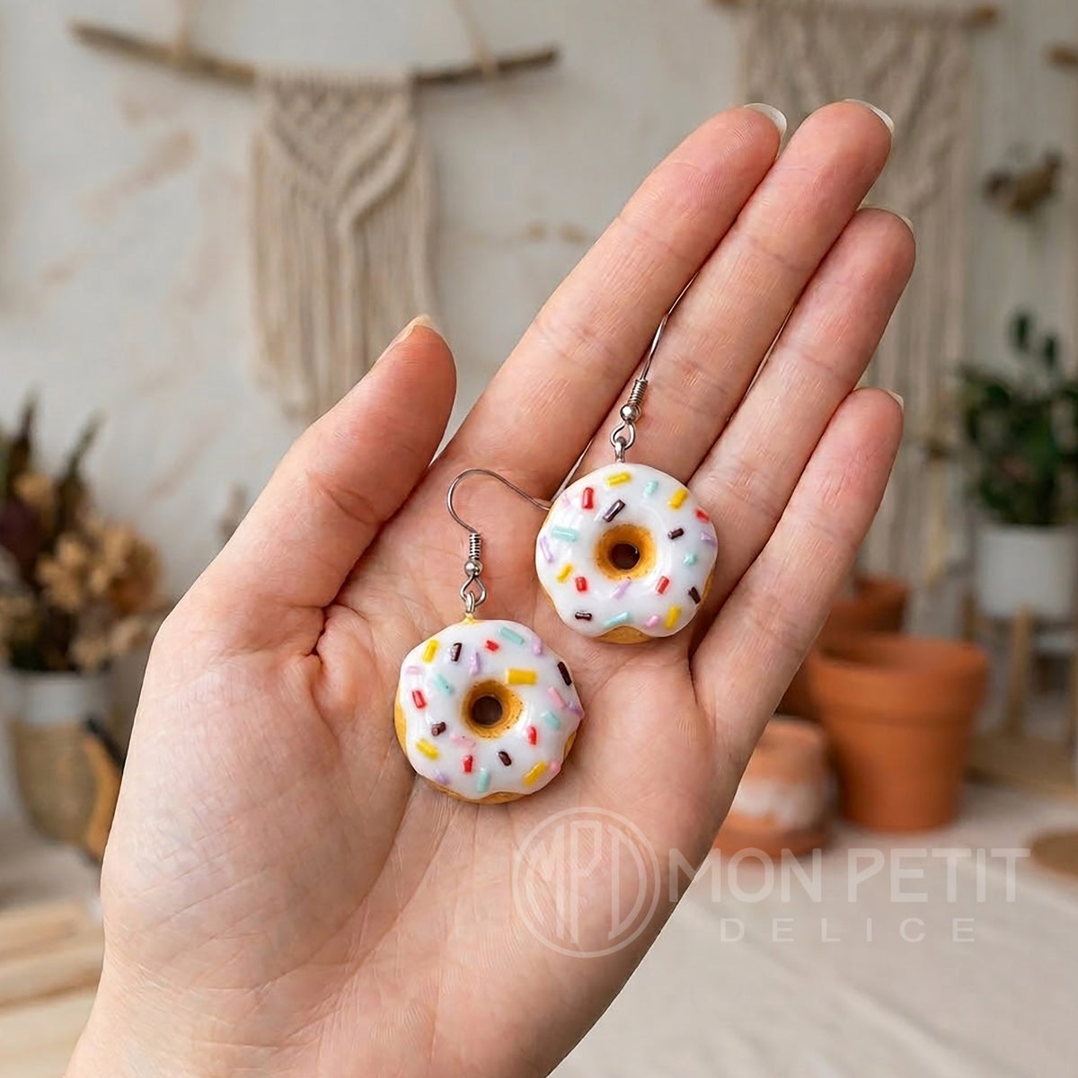 White sprinkle donut earrings held in hand to show actual scale and miniature size.